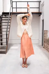 Falda midi color salmón de lino, corte recto, tiro alto y tajo lateral con botones.