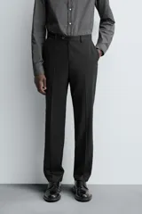 Pantalón de traje regular fit confeccionado en tejido de lana. Presenta bolsillos frontales, bolsillos traseros de vivo con botón y cierre frontal con cremallera y botón.