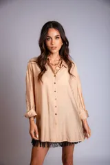 Camisa beige de corte amplio, con cuello clásico, cierre frontal con botones, mangas largas con puños abotonados y bordado floral en las mangas.