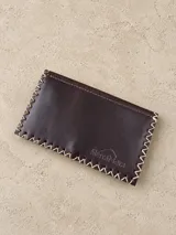 Tabaquera de cuero marrón oscuro, con costuras cruzadas en hilo crudo en los bordes y el logo de la marca grabado en la parte frontal.