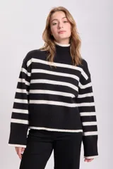 Buzo de punto con cuello alto, a rayas horizontales blancas y negras.