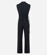Mono negro sin mangas, con cuello redondo y cierre tipo gota en la espalda. Presenta hombreras marcadas, cintura ajustable con cinturón de lazo y hebilla metálica irregular, y pantalón ancho de pierna acampanada.