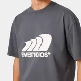 Camiseta de manga corta, corte 'boxy fit', color gris oscuro, con un gran estampado frontal en blanco que simula olas o viento y el texto 'EMESTUDIOS®' debajo.