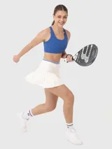 Falda deportiva blanca plisada con pretina elástica con líneas de color azul. Incluye calza interior con bolsillo.