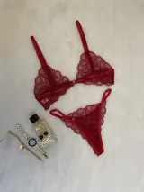 Conjunto de lencería de encaje rojo, compuesto por un bralette con cierre frontal y una tanga regulable con laterales finos.