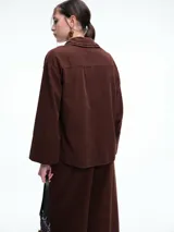 Camisa oversize de lyocell color tostado, con cuello clásico, cierre frontal de botones y mangas largas con puños anchos. Presenta un diseño de corte relajado con caída fluida.