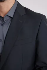 Traje de corte clásico compuesto por saco de dos botones y pantalón de vestir a juego. El saco presenta solapas tradicionales y bolsillos con solapa, mientras que el pantalón tiene un corte recto y formal.