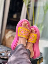 Sandalias tipo chinelas de cuero color suela, con plataforma baja y diseño de capellada con calados geométricos inspirados en motivos pampeanos.