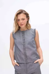 Musculosa gris a rayas verticales, con cuello redondo y detalles de volados fruncidos en la línea central delantera y en las sisas.