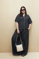 Pantalón ancho de viscosa con estampado a rayas verticales blancas sobre fondo negro, cintura elastizada y caída fluida.