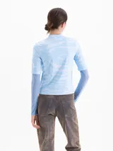 Top de cuello alto con mangas cortas, confeccionado en tejido de punto con estampado de efecto cielo y una rosa grande en el frente. Presenta un diseño entallado al cuerpo.