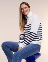 Buzo de frisa blanca con rayas horizontales azul marino, cuello alto con medio cierre y mangas largas.