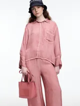 Camisa de manga larga color rosado, confeccionada en viscosa teñida en frío con efecto gastado. Presenta un corte relajado, bolsillo delantero y puños amplios.