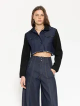 Campera corta de denim azul con mangas largas negras y cuello clásico negro.