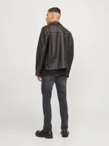 Jean de corte slim fit con tiro bajo, confeccionado en denim elástico de color gris oscuro con efecto lavado. Presenta diseño clásico de cinco bolsillos, cierre frontal con botón y costuras reforzadas.