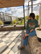 Sweater verde tejido con cuello redondo y diseño de cabeza de vaca en cuero marrón con bordados a mano en color beige.