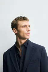 Blazer de corte slim fit confeccionada en tejido con viscosa, con cuello de solapas de muesca, manga larga con puños abotonados, bolsillo de vivo en el pecho, bolsillos con solapa en la cadera y cierre frontal con botones.