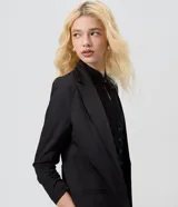 Blazer sastre alargado de color negro, confeccionado en poliéster con elastano, con solapas clásicas y mangas largas con frunce.