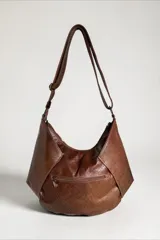 Cartera bandolera de cuero marrón con detalles en cuero con pelo con estampado animal print. Cuenta con diseño geométrico, correa ajustable y cierre superior.