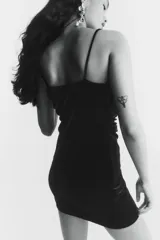Vestido corto negro, ajustado al cuerpo, con breteles spaghetti finos y escote drapeado tipo cascada. Presenta frunces laterales que generan un efecto drapeado en la parte delantera.