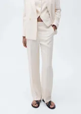 Pantalón de vestir color crema, de corte recto, con cierre de botón y cremallera, tiro medio y bolsillos laterales. Ideal para fiestas y ceremonias.