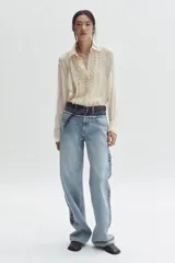Jean de corte holgado y pierna recta confeccionado en denim de algodón rígido. Presenta un diseño bicolor con paneles en tonos contrastantes, costura desflecada en la cintura y franjas laterales. Cuenta con diseño de cinco bolsillos, cierre con botón y tachas metálicas con logo grabado.