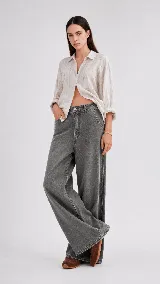 Pantalón de jean color naranja con tiro medio, diseño de pierna ancha y cinco bolsillos. Presenta costuras con pespuntes a contratono.