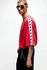 Remera de algodón oversized color rojo, con cuello redondo y mangas cortas raglán decoradas con una franja blanca lateral con logotipos negros de Lotto. Cuenta además con el logo de la marca estampado en el centro del pecho.