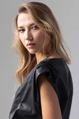 Top color beige de simil cuero liviano, con escote cruzado y acceso por cierre invisible lateral. Sin mangas con espalda cerrada y frunces en hombros.