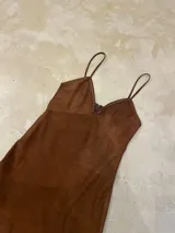 Vestido midi de antílope genuino color chocolate, con breteles finos, escote en V con detalle de pasamanería color cobre y falda de corte irregular.