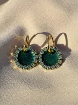 Aros colgantes dorados con dije circular de resina color turquesa, bordeado con strass. El arito es de acero quirúrgico.