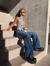 Pantalón de jean azul de corte acampanado con costuras verticales en el frente.