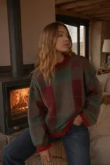 Sweater de punto con diseño de cuadros tartan en escala XL, en tonos marrones, verdes y bordó. Presenta un detalle de volados en el cuello, puños y ruedo, con un corte oversize.