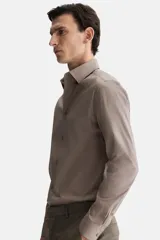 Camisa de hombre color marrón claro, de corte slim fit, con cuello italiano, tapeta lisa y canesú en la espalda. Tiene mangas largas con tapeta y botón, puños ajustables con botón y bajo ligeramente redondeado.