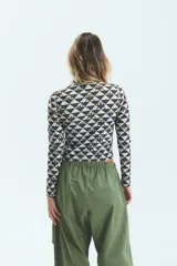 Polera de manga larga con cuello alto, confeccionada en lycra estampada con diseño geométrico de triángulos y monograma exclusivo de la marca.
