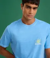 Remera de hombre, corte comfort, manga corta, color celeste con efecto desteñido y un pequeño estampado frontal de un sol sonriente.