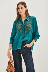 Camisa de viscosa color verde esmeralda, con cuello clásico, mangas largas con puños abotonados y bordados decorativos en color dorado en la parte frontal.