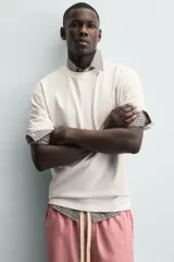 Camiseta blanca de corte relajado (relaxed fit) con cuello redondo y manga corta. Presenta un estampado grande en la espalda que simula dados rojos con letras y corazones.