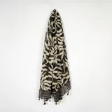 Pashmina de tela ligera con estampado de hojas en tonos negro y beige, terminada con flecos en los extremos.