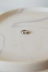Anillo abierto de acero quirúrgico con diseño de superficie irregular y acabado brillante.