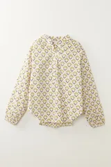 Camisa blanca con estampado floral en tonos ocre y marrón, cuello mao y mangas largas con puños elásticos.