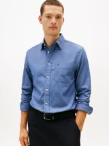 Camisa de manga larga azul con cuello abotonado, cierre frontal con botones y un bolsillo de parche en el pecho con el logo de la marca bordado. Confeccionada en algodón.