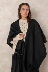 Ruana abierta de color beige, confeccionada en tejido de punto con terminación de flecos en el ruedo.