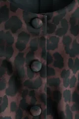 Blusa de sarga con estampado de leopardo, ajuste entallado, escote redondo, botones forrados frontales y mangas cortas abullonadas con pliegues en los hombros.