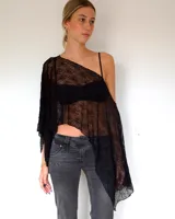 Capa de encaje negro con diseño asimétrico y caída holgada, ideal para usar sobre otras prendas.