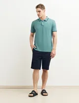 Remera polo azul marino con ribetes blancos en el cuello y en los bordes de las mangas corta, y cierre frontal de botones.