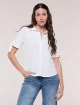 Camisa blanca de manga corta con cuello solapa, cierre frontal de botones, detalles bordados al tono en el pecho y lazos para anudar en las mangas.