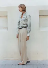 Pantalon de corte wideleg color beige, con tiro medio, detalle de pinzas frontales, trabillas para cinturon y cierre frontal con boton, gancho y cremallera.