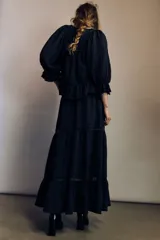 Pollera larga de color negro con elegantes alforzas e inserciones de encaje. Modelo de corte holgado con cintura elástica en la parte posterior.