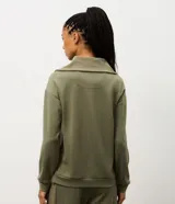 Buzo deportivo de corte oversized en color verde oliva, confeccionado en tejido modal con mezcla de poliéster y elastano. Presenta cuello alto con cierre frontal de cremallera y paneles frontales con textura acanalada. Incluye mangas largas con puños elásticos ajustados.